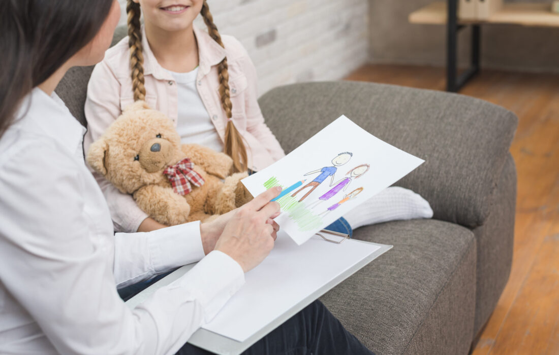 close-up-professional-psychologist-looking-family-drawing-drawn-by-girl-with-teddybear