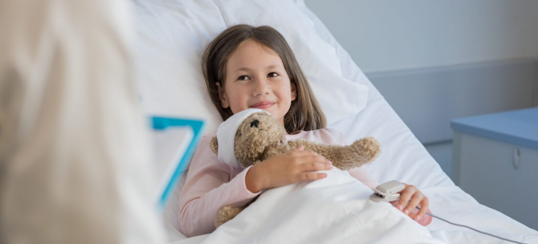 Smiling little girl with oxygen saturated probe resting on hospital bed. Girl patient looking at doctor with a smile. Child and doctor at medical clinic.