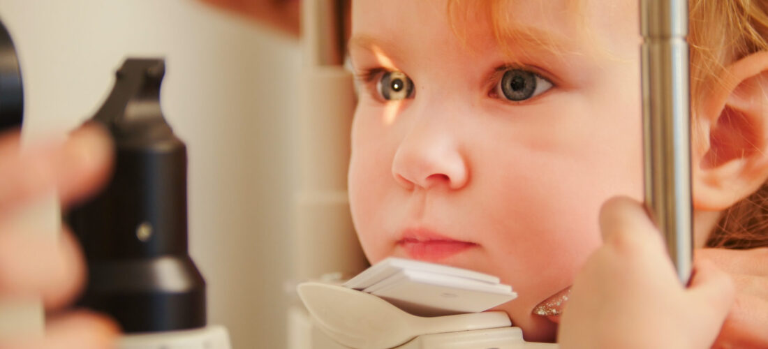 Child's optometry concept - little girl checks eyesight in eye ophthalmological clinic, telephoto
