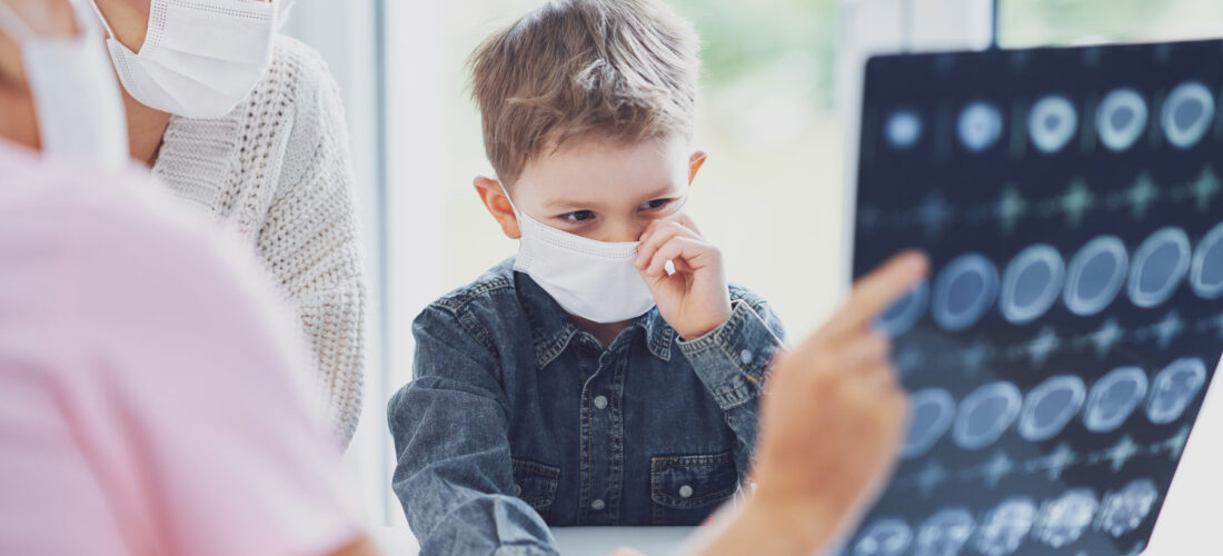 Doctor discussing x-ray results with mom and her son all wearing masks due to covid-19